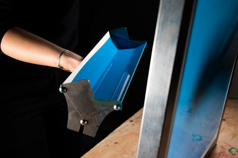 A scoop coater coating a screen with blue emulsion