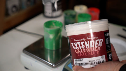 a bucket of extender base with a scale in the background