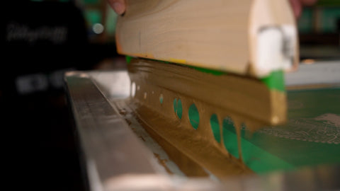 gold ink dripping off a squeegee onto a screen