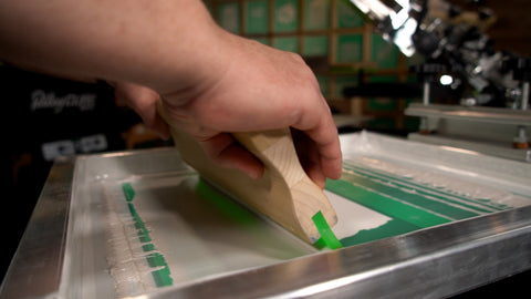 A printer pulls a squeegee of pearl ink over a screen