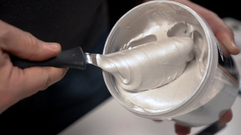 A spatula stirs up Pearl metallic ink in the bucket