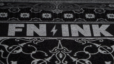 "FN-INK" printed on a t-shirt in silver ink