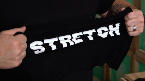 a person stretching a shirt with "stretch" written in white ink