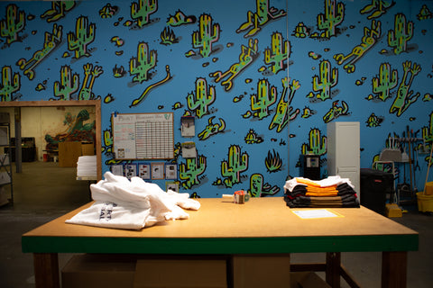 A table with folded shirts on it and a cactus-printed wall