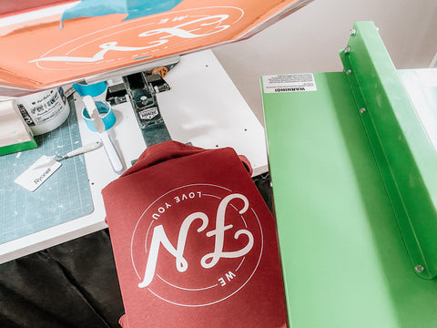 A shirt sits on a press with a flash dryer nearby