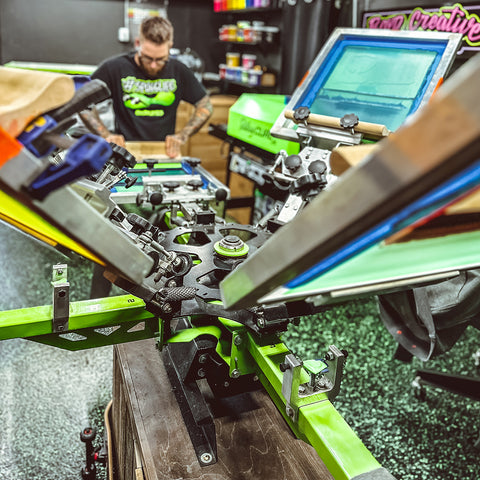 A zoomed-in shot of a riley hopkins press in motion with a printer standing on one end of the print station