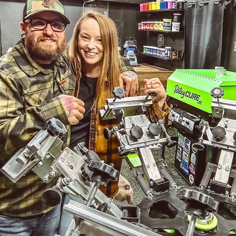 a man and a woman smile at the camera over their Riley Hopkins press