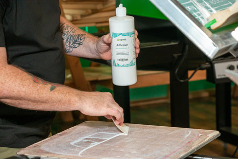 a hand holds up a bottle of water-based pallet adhesive