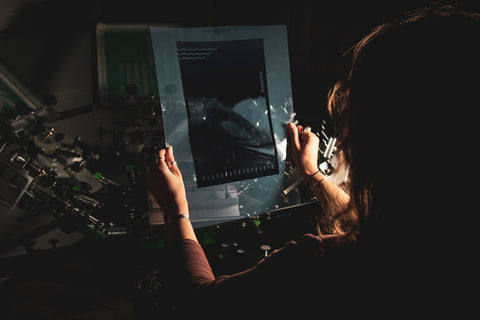 A person holds up a film transparency with the image of a wave on it