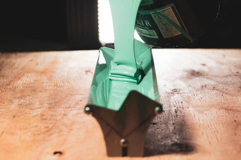 person pouring baselayr complete emulsion into a scoop coater