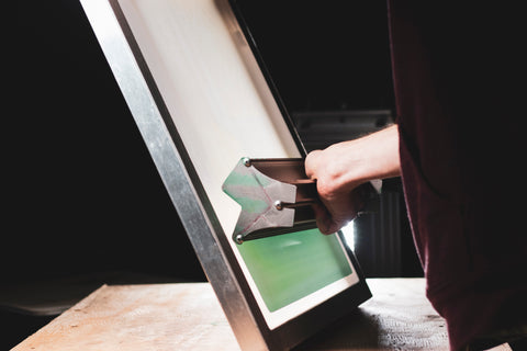 A hand coats a screen with green emulsion