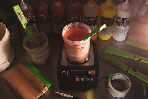 a bucket of mixed colored water-based ink sits on a scale with the Fusion mixing system behind it