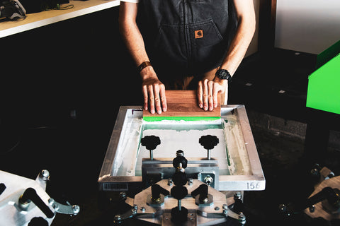 a printer pulls a squeegee across a screen