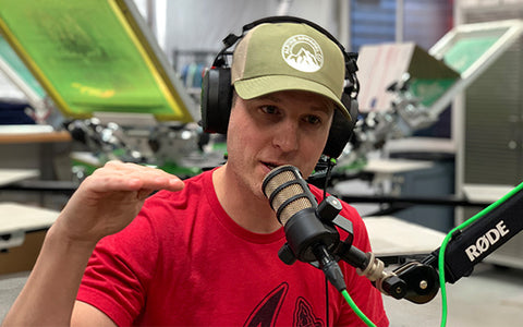 Jesse Poteet in front of a Riley Hopkins Press on a microphone