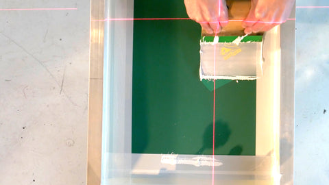 A screen printer uses a small squeegee to print a left chest print