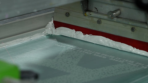 an automatic squeegee pulling white ink over a screen