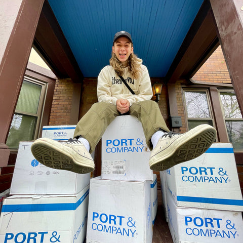 A man wearing a hat sits on piles of boxes