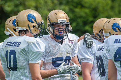 Football players stand in a huddle