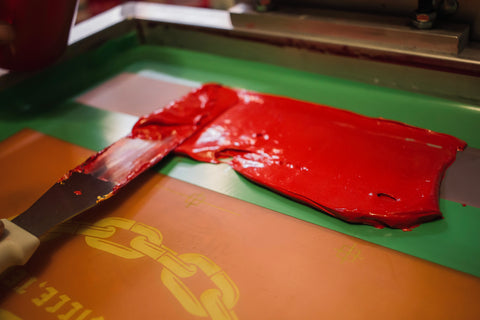 Una espátula de tinta con tinta roja deslizada por una pantalla