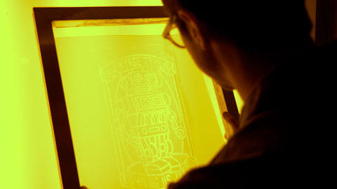 A man with glasses looks at a screen with a design under yellow light