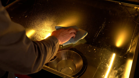 A hand wipes a cloth over the glass of an exposure unit to clean it