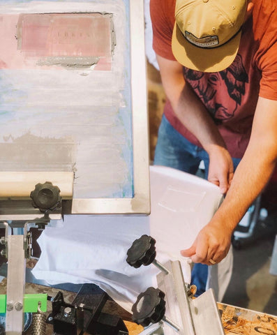 a man adjusts a shirt on a screen printing press