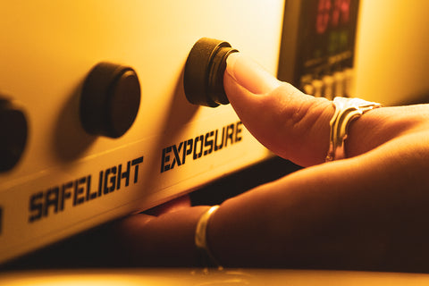 A thumb pressing the exposure button on an exposure unit