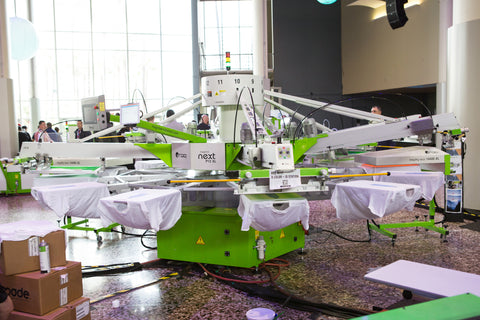 A ROQ automatic screen printing press in a warehouse with white shirts loaded on the platens