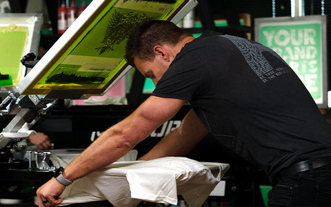 a man loads a white shirt onto a 250 press