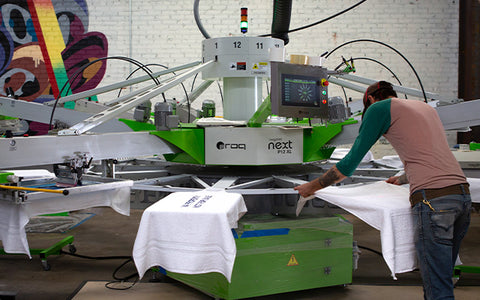 a man leans over a 12 color automatic press