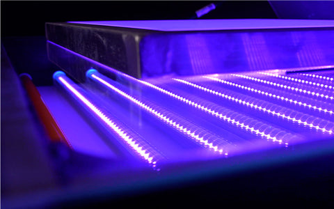 Una unidad de exposición con luces LED azules encendidas, exponiendo una pantalla con marco de aluminio