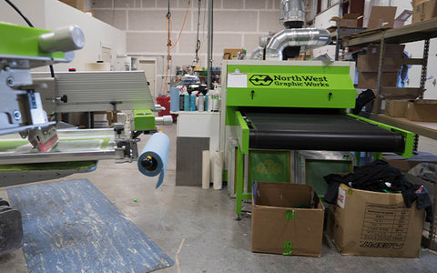 a large dryer sits by an automatic press with blue towels hanging off them