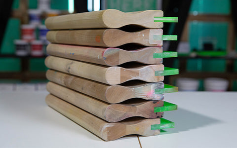 a stack of wood-handled squeegees sits on a press cart