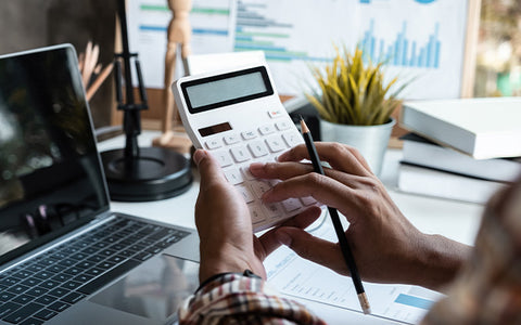 a person holds a calculator at a desk