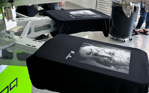 a grayscale print of a man's face on a black shirt sits on a platen of a ROQ automatic press