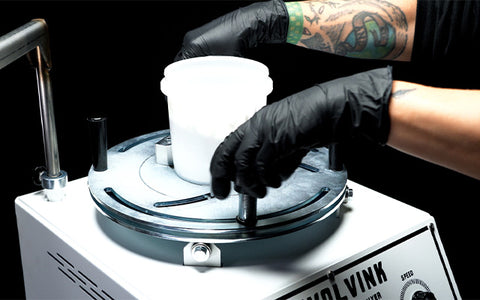 person putting a container on revolvink mixer
