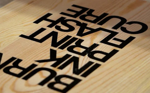 a piece of wood printed with the words "burn ink print flash cure"