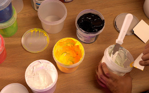 containers of yellow, black, and white ink next to an ink mixing container