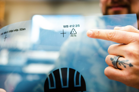 person pointing to recycling symbol on film