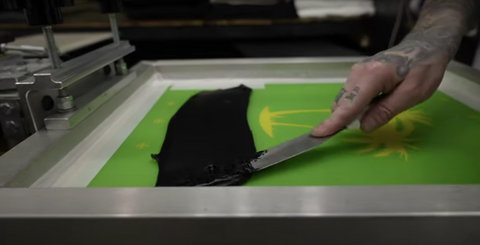 person putting black ink on a screen