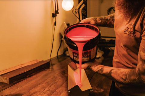 person pouring emulsion into a scoop coater