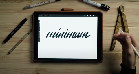 Una mano descansa junto a la palabra de caligrafía "mínimo"