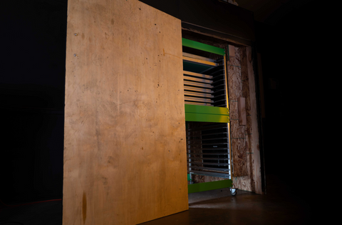 Una caja seca hecha de madera contrachapada se encuentra en un cuarto oscuro.