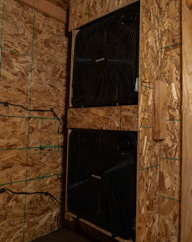 two black box fans embedded into the wall of a dry box