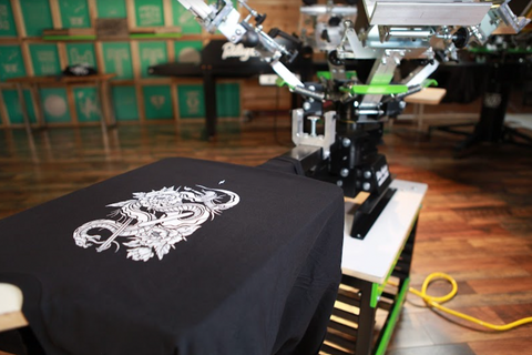 A white design on a black shirt sits on a Riley Hopkins 4x1 press
