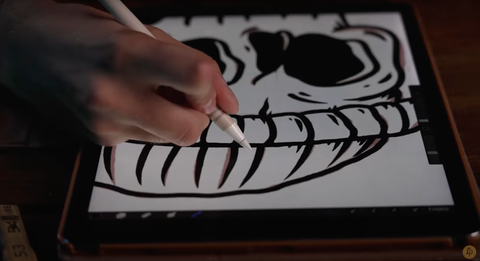 A hand draws the beanie of a skeleton with a pencil
