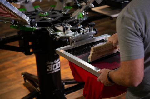 A man pulls black blocker base ink down a screen