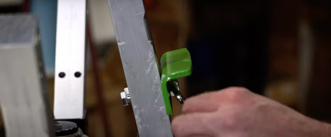 A hand uses a wrench to tighten the color arm of a press