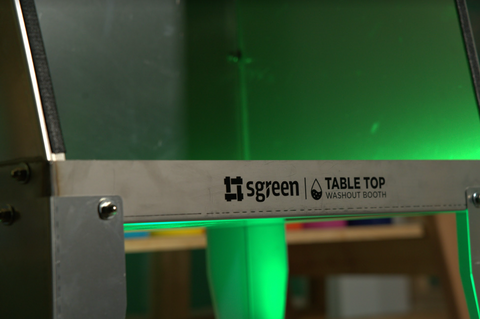 A tabletop washout booth sits on a counter with green lighting