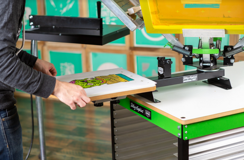 a pair of hands reach for a test printing pellon on a printing press